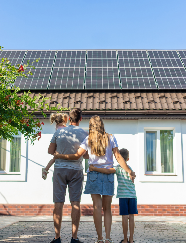Family enbracing in front of black solar panels house